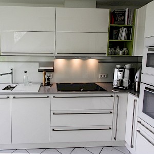 Schüller Küche in Münster mit Quarzkompositplatte und grünen Regalen