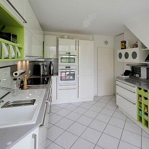 Schüller Küche in Münster mit Quarzkompositplatte und grünen Regalen